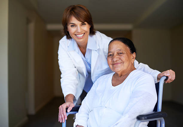 A doctor assisting an elderly patient sitting in a wheelchair